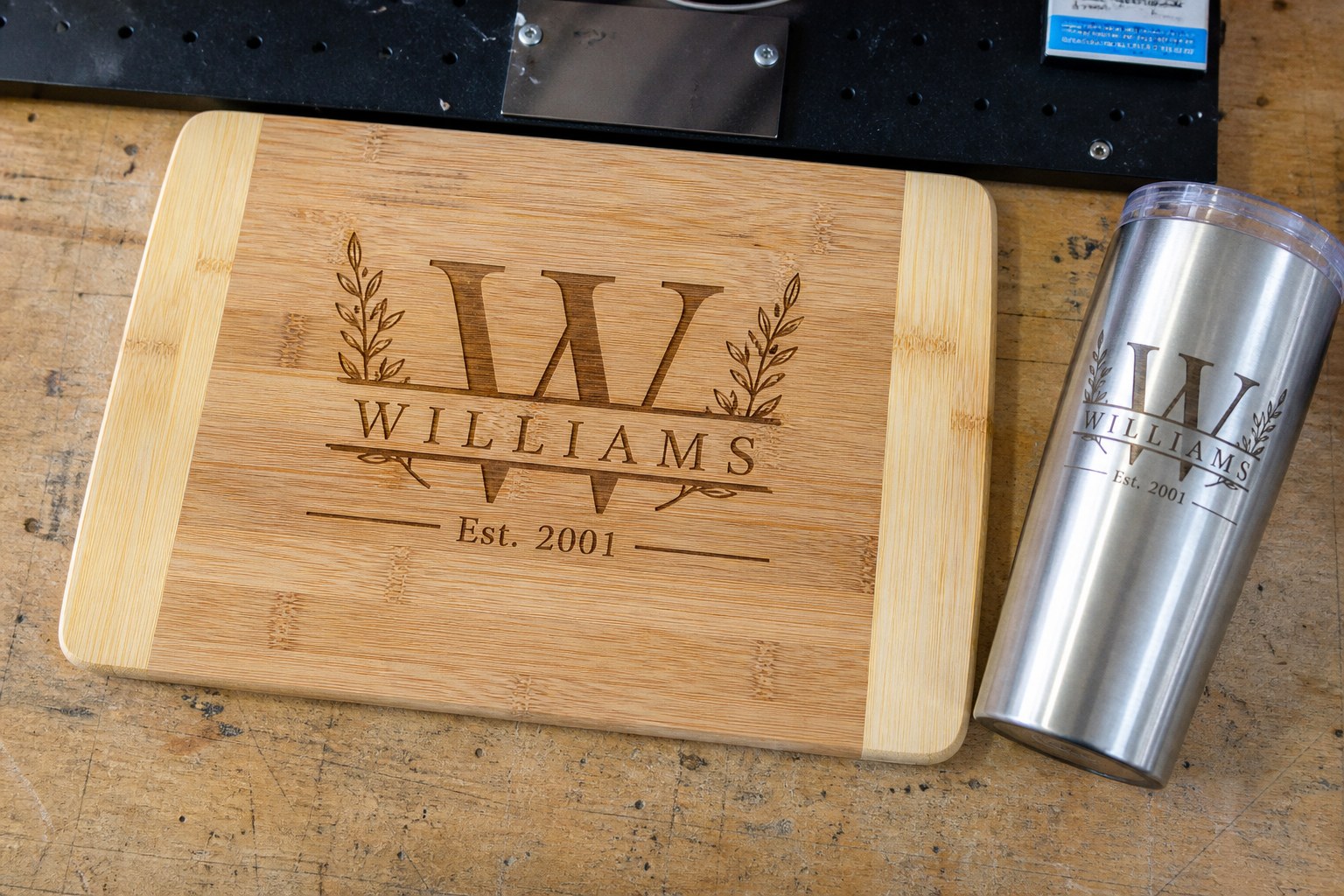 Laser-engraved bamboo cutting board and matching tumbler with a Williams family mark