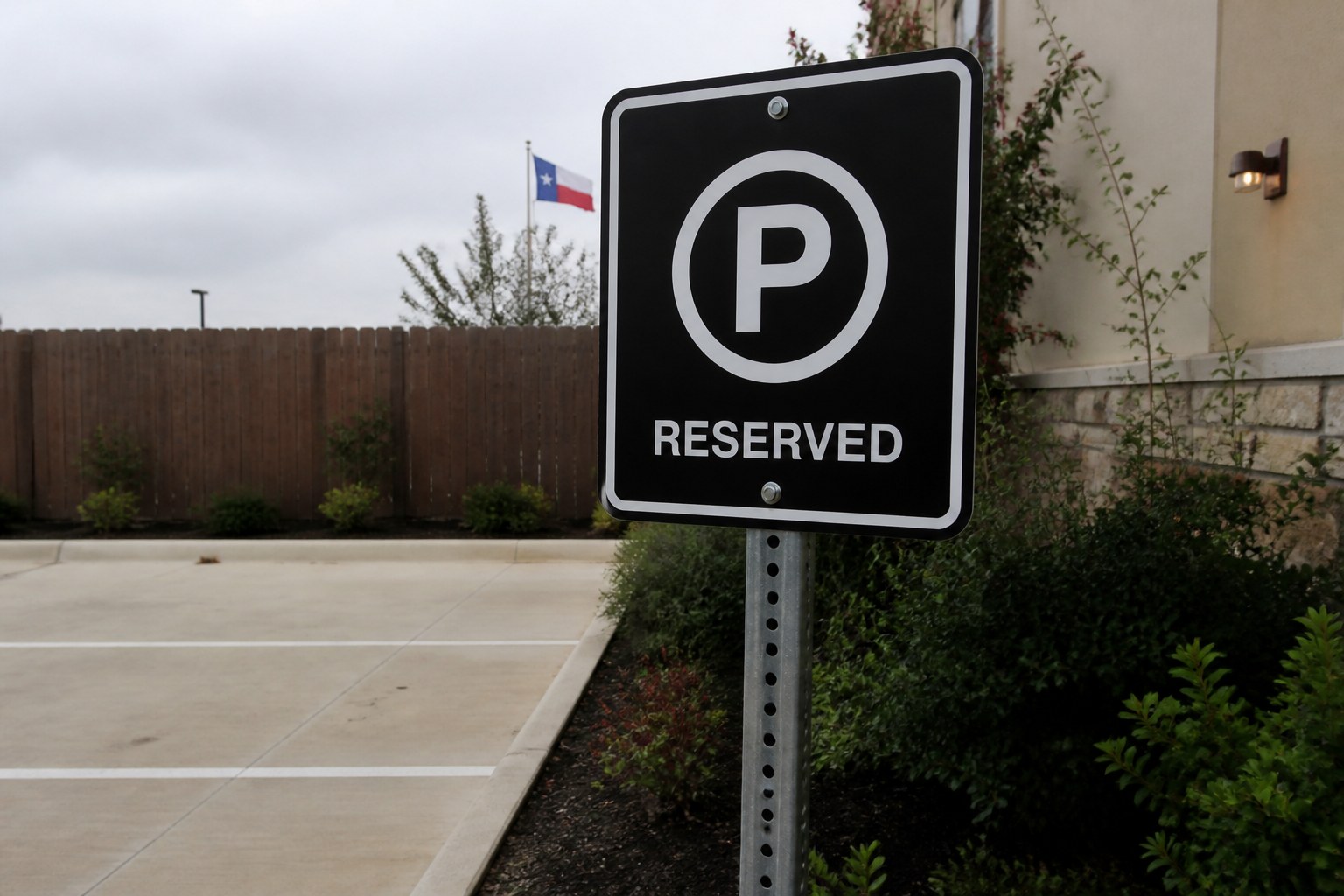 Reserved parking sign with a white P on a metal post beside a parking lot